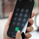 a hand holding a phone with a number on the screen