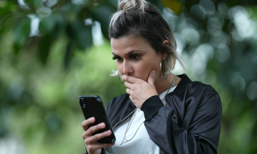 Kvinna förvånad tittar i mobilen